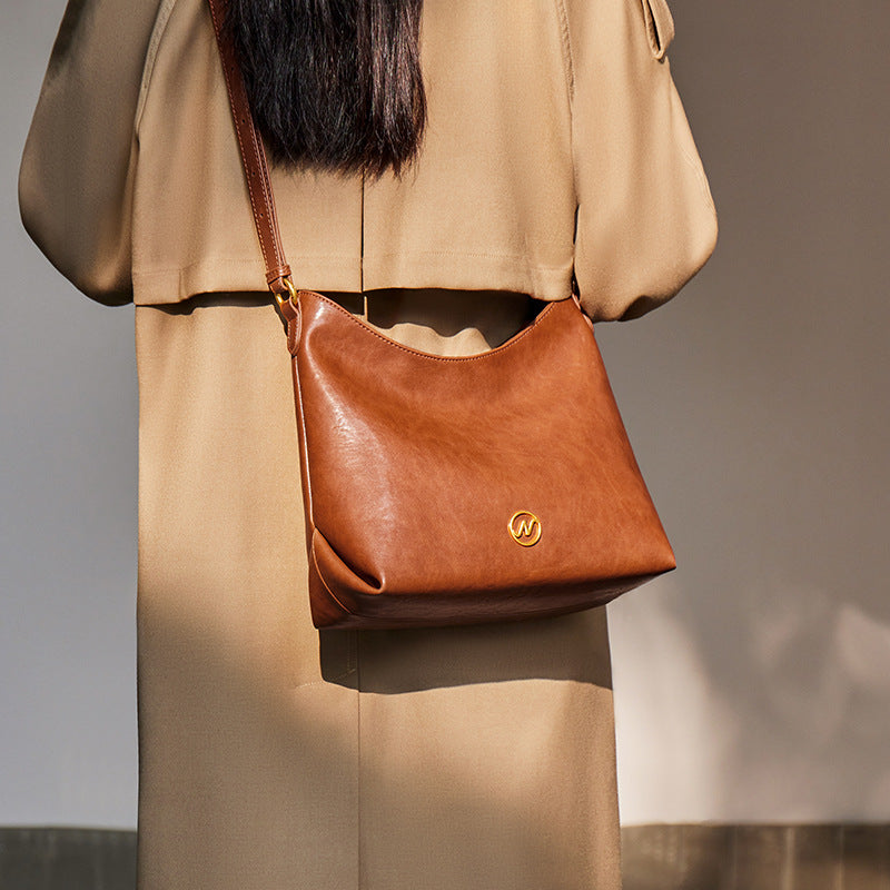 slouchy leather shoulder bag with gold emblem – AURX