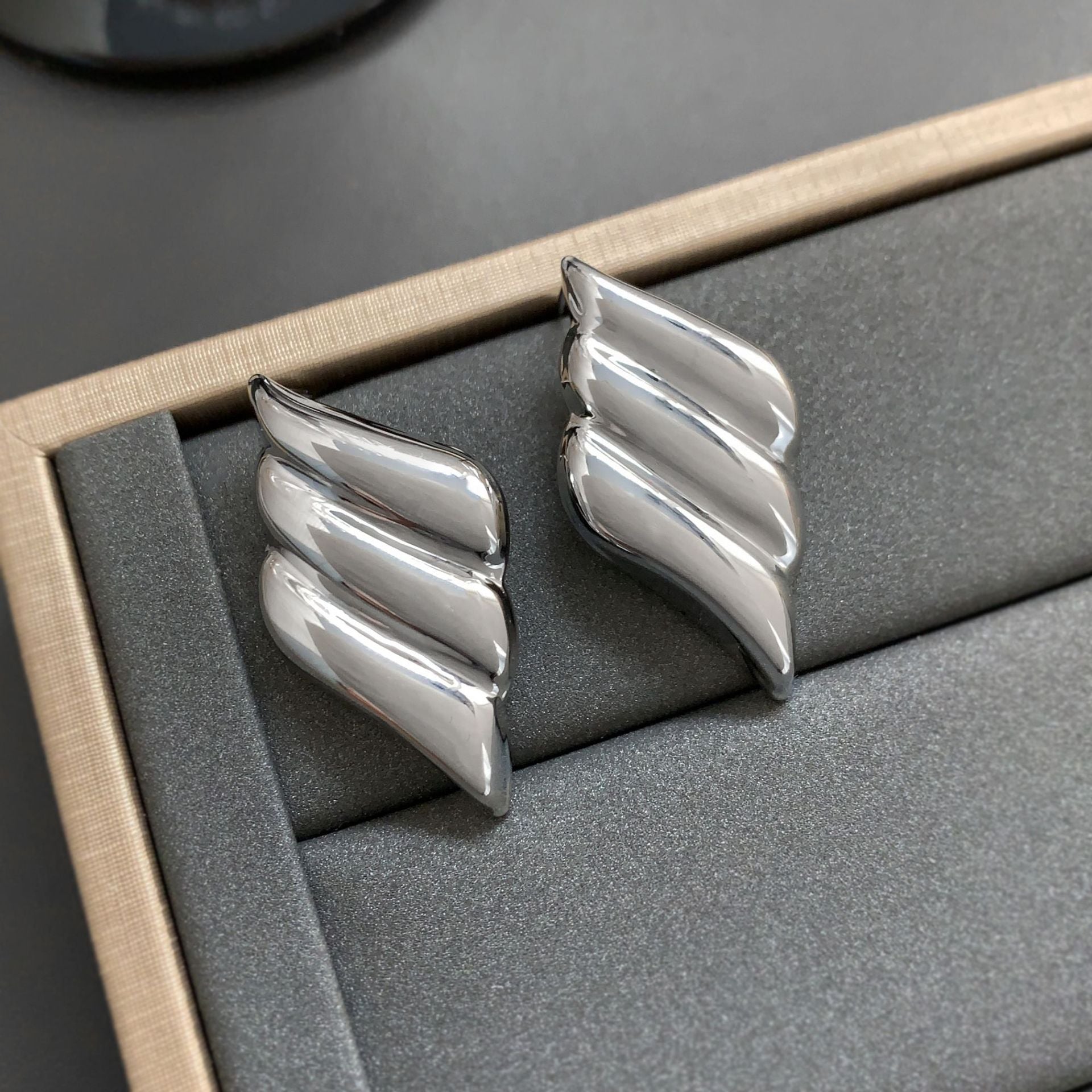Polished wing-shaped stud earrings with sculpted curves - Ajurti