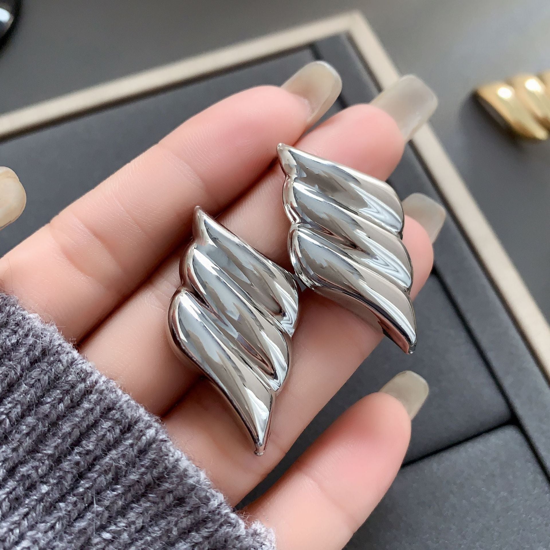 Polished wing-shaped stud earrings with sculpted curves - Ajurti