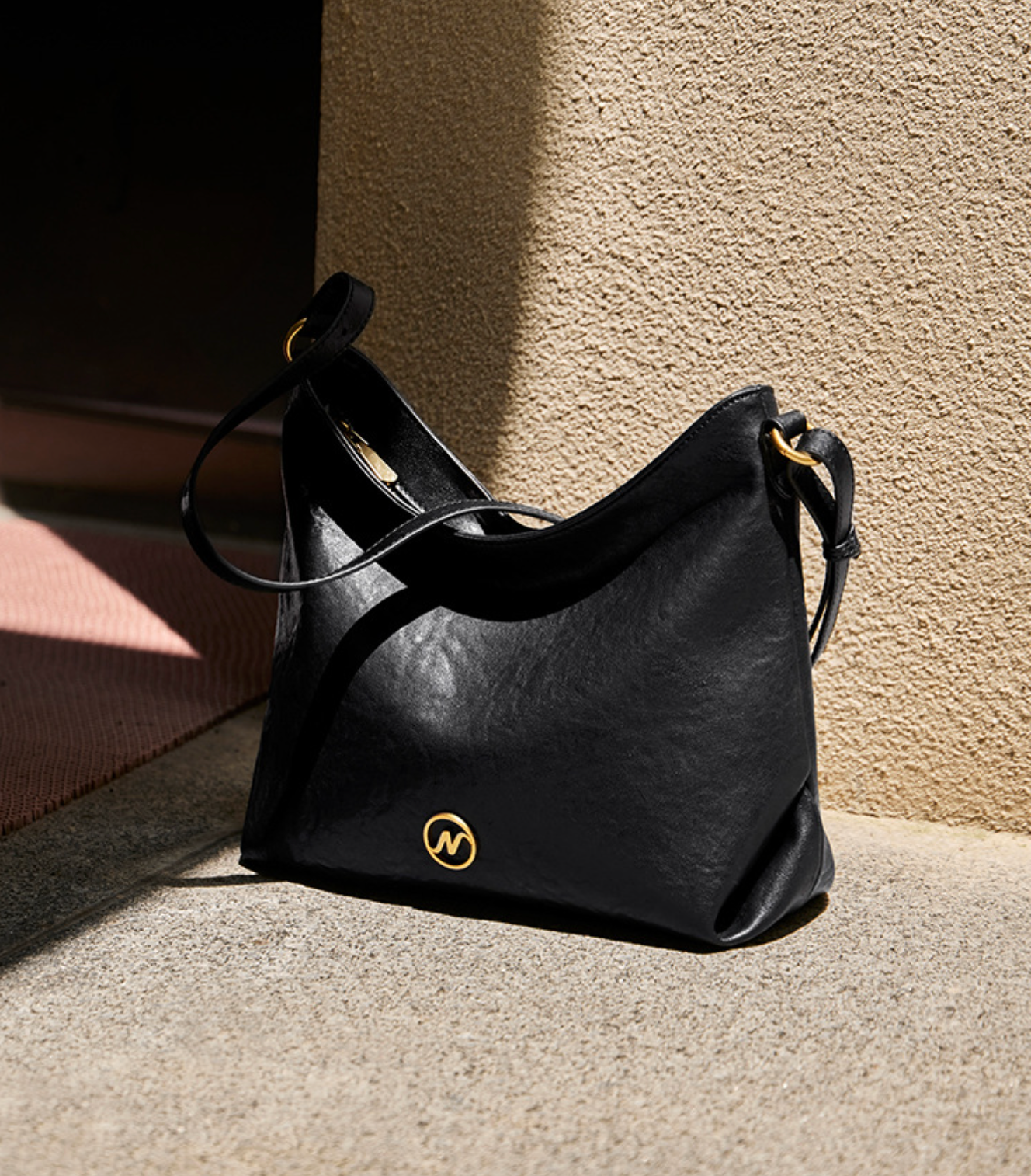 slouchy leather shoulder bag with gold emblem – AURX